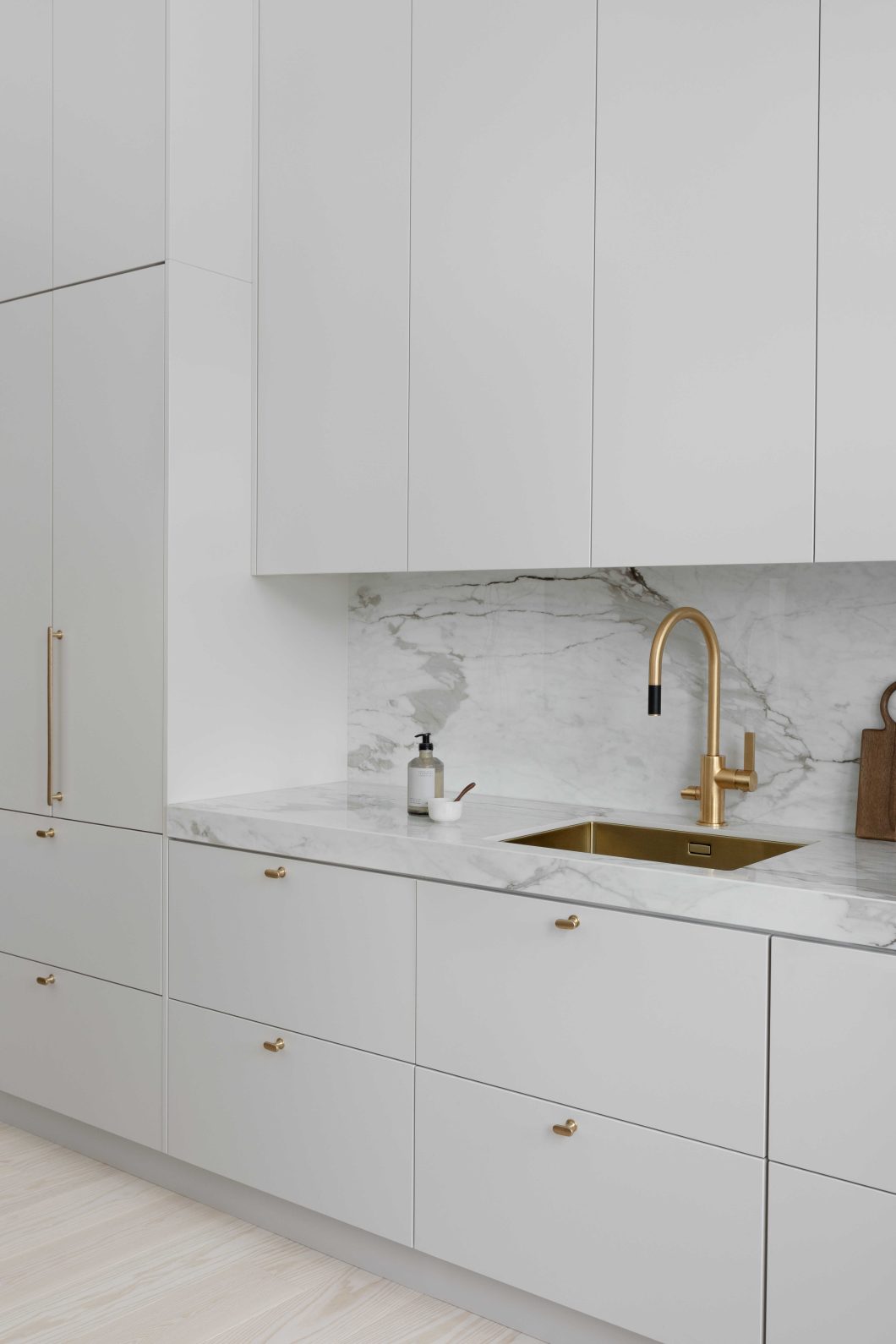 Moderni designkeittiö, jossa hiekan sävyinen mulperi-maalattu kaapisto, marmorikuvioinen keraaminen työtaso ja välitila.