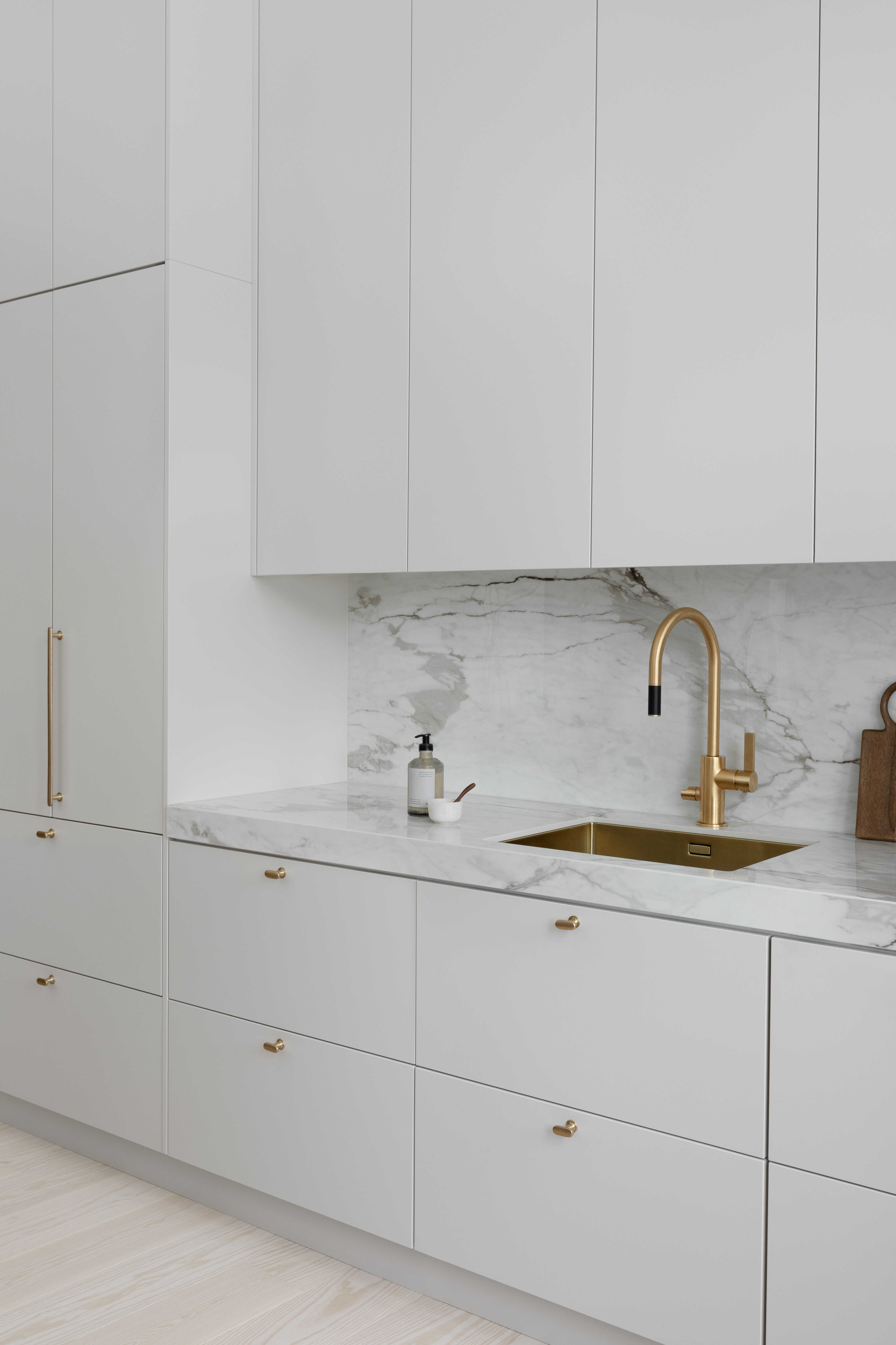 Moderni designkeittiö, jossa hiekan sävyinen mulperi-maalattu kaapisto, marmorikuvioinen keraaminen työtaso ja välitila.